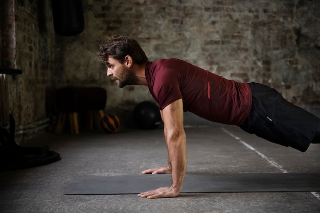 Мужчина среднего роста тренируется с ковриком для йоги