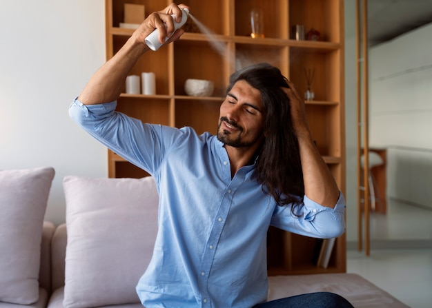 Medium shot man using dry shampoo  at home