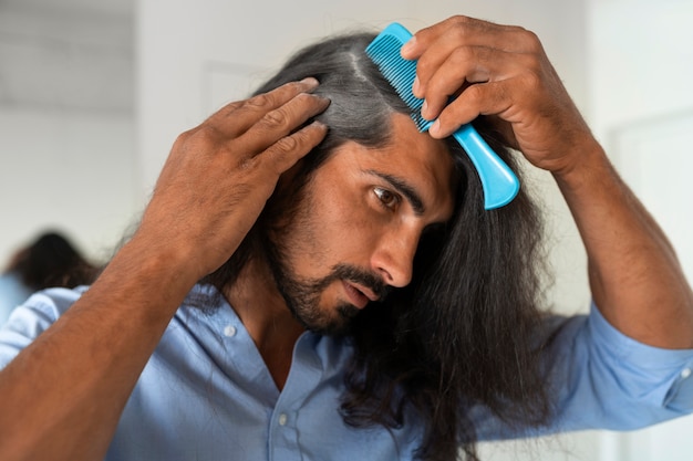 Foto gratuita uomo di tiro medio che usa shampoo a secco a casa