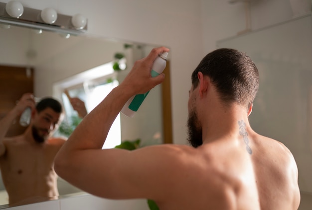 Free photo medium shot man using dry shampoo