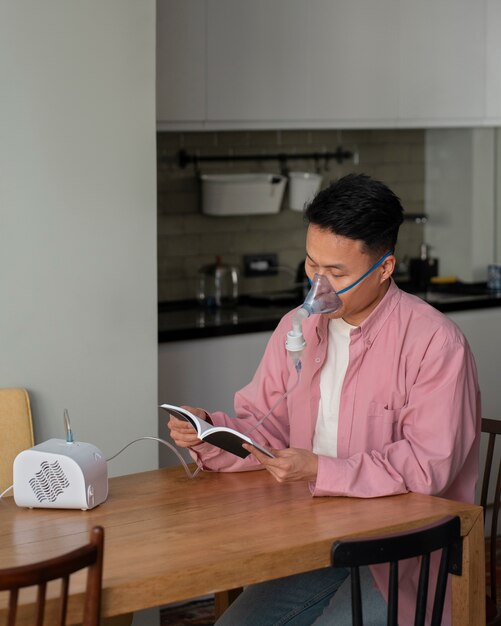 Free photo medium shot man using nebulizer at home