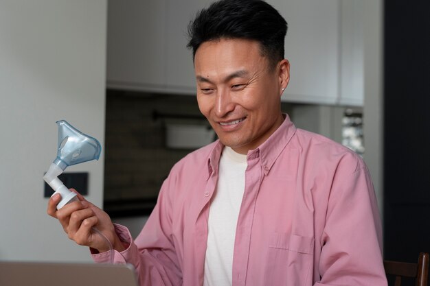 Free photo medium shot man using nebulizer at home