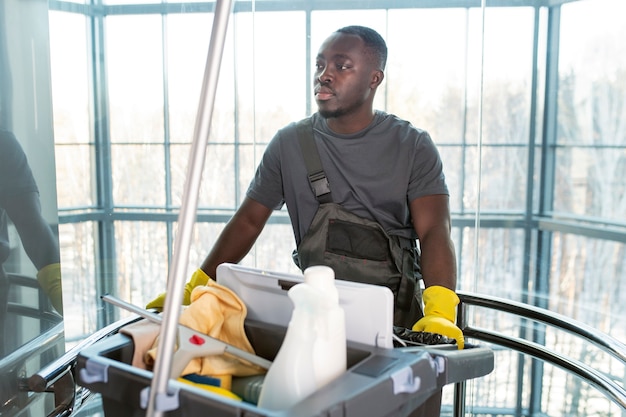 Medium shot man walking with cleaning cart