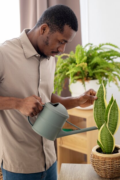 Medium shot man watering plant at home