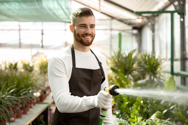 Medium shot man watering plants