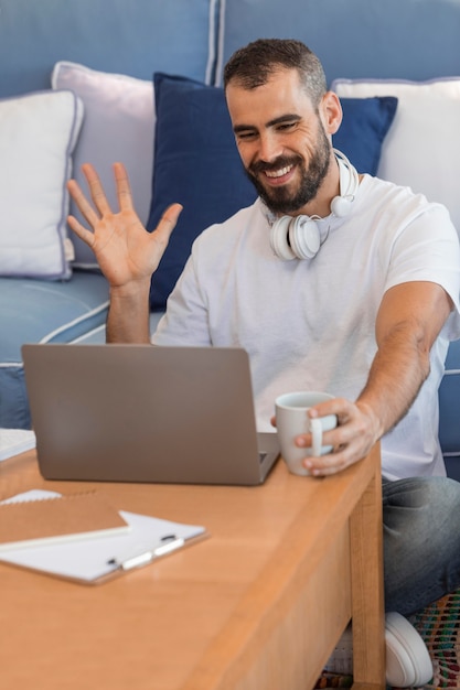 Medium shot man waving at laptop