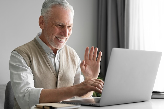 Medium shot man waving at laptop