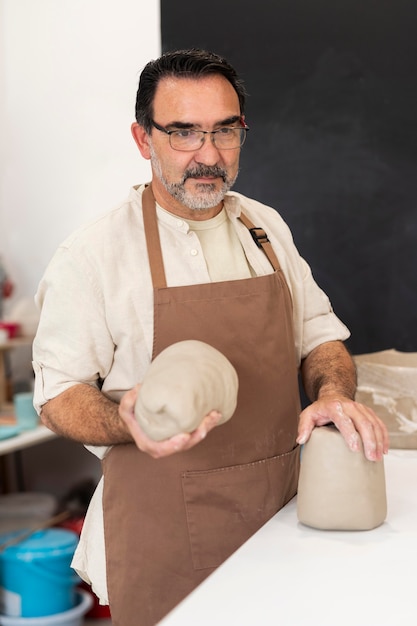 Medium shot man with apron and clay