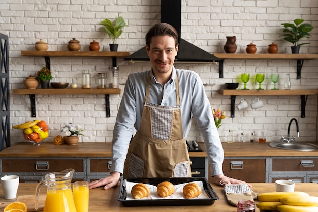 Free photo medium shot man with croissants on tray