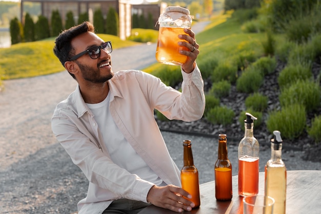 Foto gratuita uomo di tiro medio con delizioso kombucha all'aperto