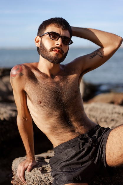 無料写真 海辺で毛むくじゃらの胸を持つミディアムショットの男
