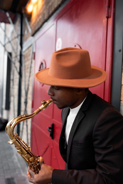 Foto gratuita uomo di tiro medio con cappello che suona allo strumento
