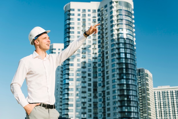 Free photo medium shot man with helmet pointing up