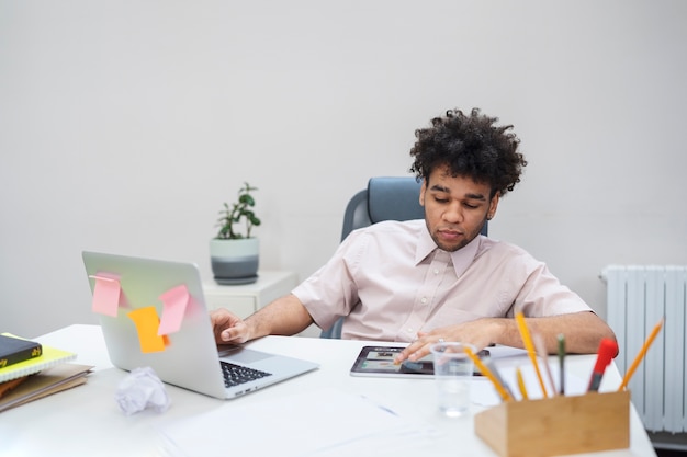 Medium shot man with laptop and tablet