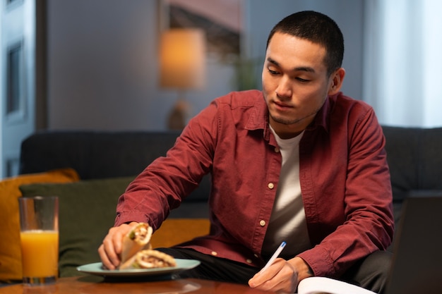 Free photo medium shot man with  paper-wrapped sandwich