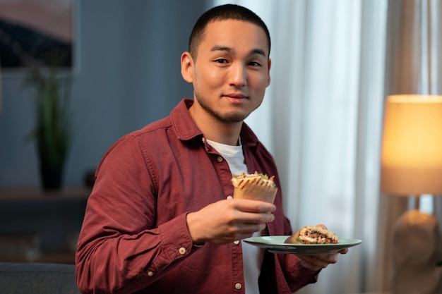 Free photo medium shot man with  paper-wrapped sandwich