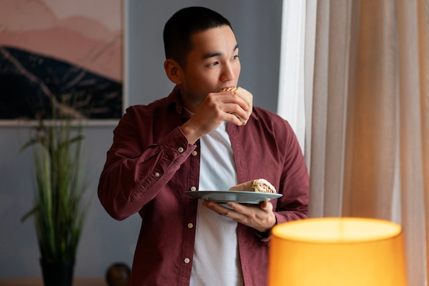 Free photo medium shot man with  paper-wrapped sandwich