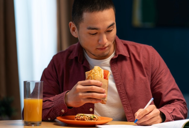 Foto gratuita uomo di media portata con un panino avvolto in carta.