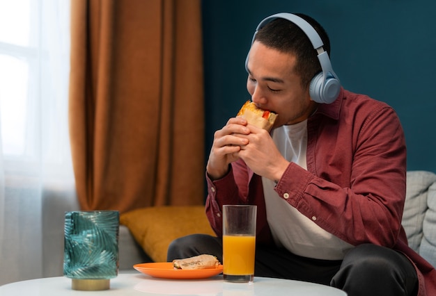 Free photo medium shot man with  paper-wrapped sandwich