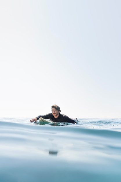 Uomo di tiro medio con tavola da surf