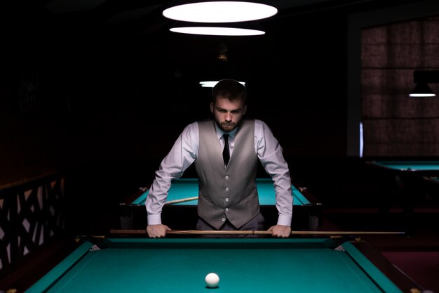 Medium shot man with vest holding pool cue 