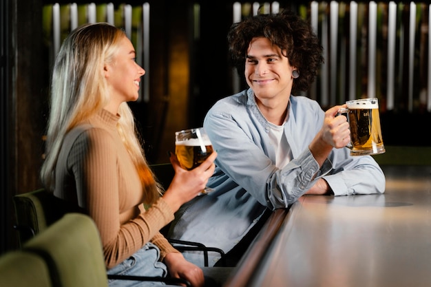 Medium shot man and woman with beer mugs