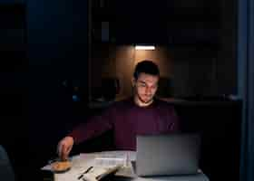 Free photo medium shot man working late at night on laptop