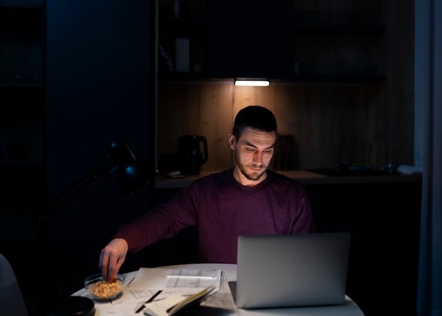 Мужчина среднего роста, работающий поздно ночью на ноутбуке