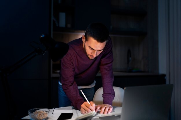 Medium shot man working late at night on laptop