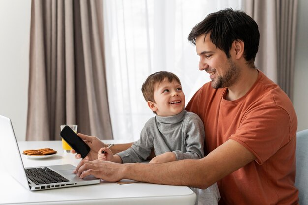 Medium shot man working remotely with kid