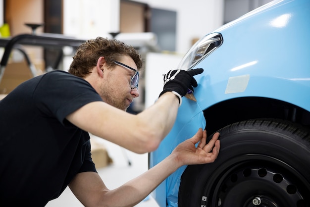 青いカバーで車を包むミディアムショットの男