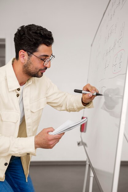 Medium shot man writing on whiteboard