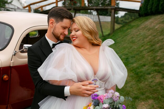 Medium shot married couple posing with vintage car