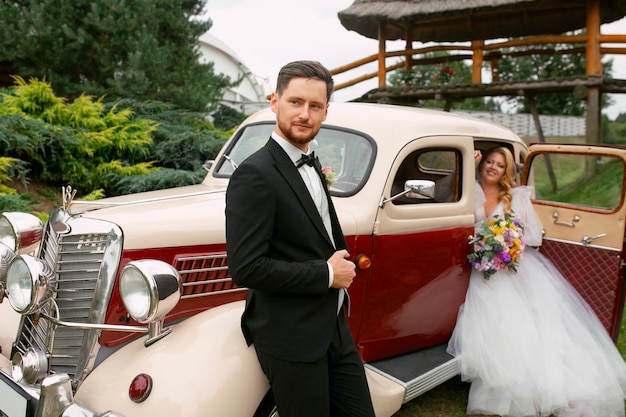 Free photo medium shot married couple posing with vintage car