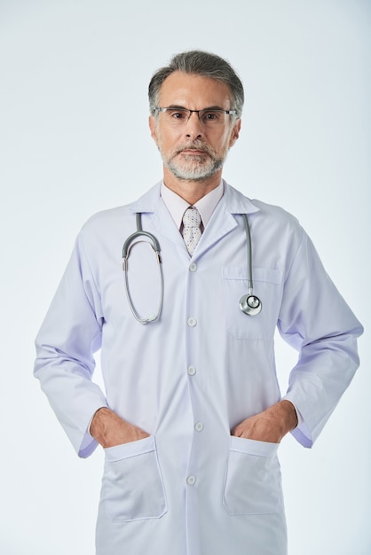 Medium shot of medical specialist standing with arms in pockets looking at camera