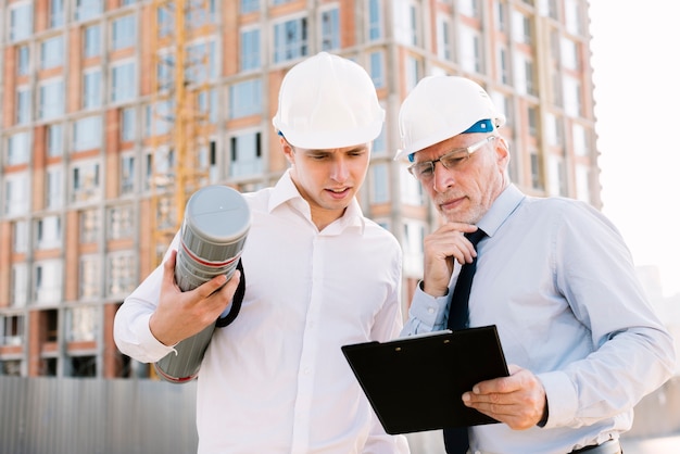 Free photo medium shot men with helmets and clipboard