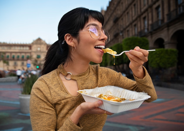 Бесплатное фото Мексиканка среднего размера ест еду ранчеро