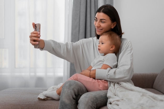 Free photo medium shot mother and baby taking selfie