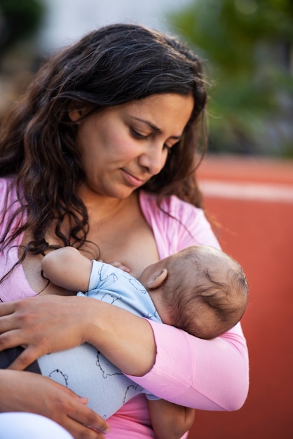 Medium shot mother breastfeeding outside