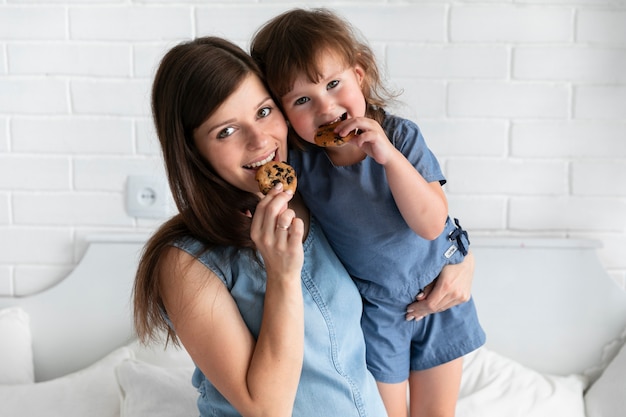 Madre e figlia del colpo medio che mangiano i biscotti del cioccolato