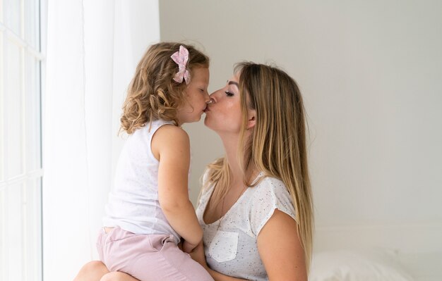 Medium shot mother and daughter kissing