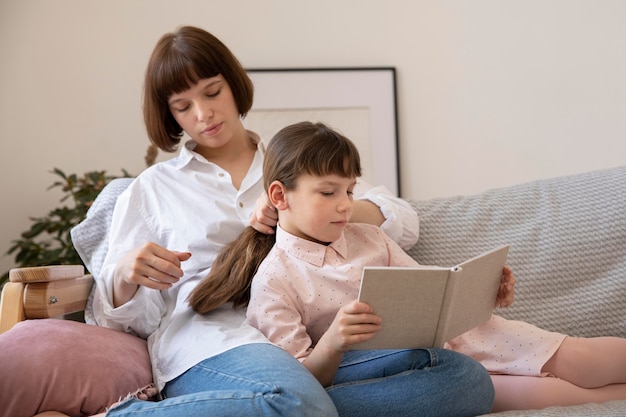 Medium shot mother and daughter reading book