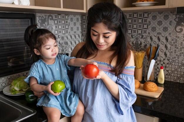 Medium shot mother and girl in kitchen