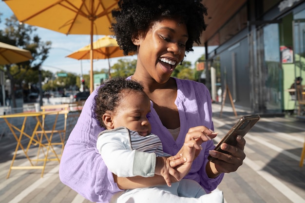 Free photo medium shot mother holding baby outdoors