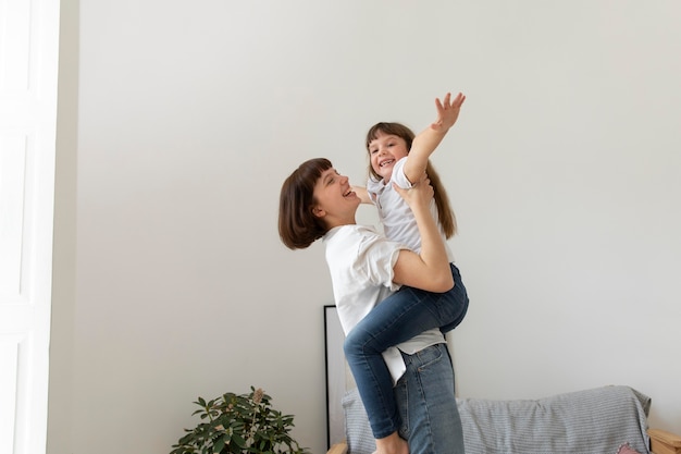 ミディアムショットの母親が女の子を抱いている