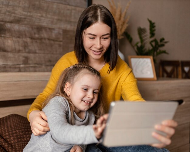 子供とラップトップを保持しているミディアムショットの母親