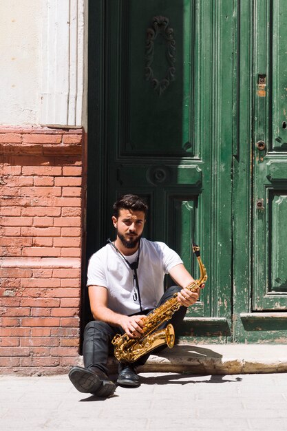 Medium shot musician sitting and posing with sax