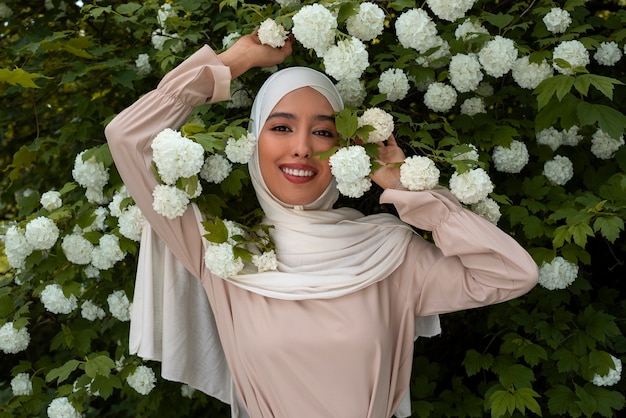 Foto gratuita donna musulmana del colpo medio che posa con i fiori