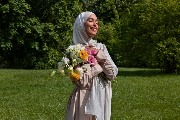 花とポーズをとるミディアムショットのイスラム教徒の女性