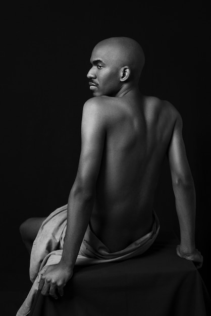 Medium shot naked man posing on chair black and white